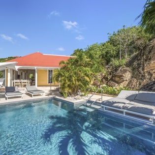 Soak up tropical sunshine beside your private pool, surrounded by lush palms and dramatic hillside views in this serene Caribbean-style retreat.