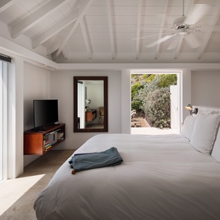 Wake up to lush hillside views and gentle island breezes. Your peaceful retreat features soaring vaulted ceilings, direct garden access, and natural light flooding through floor-to-ceiling windows.