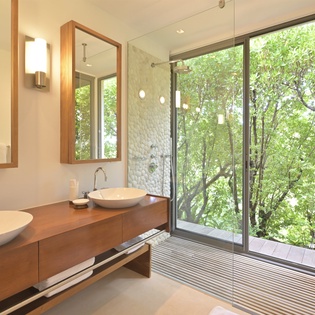 Unwind in your spa-like bathroom with twin vessel sinks and a glass-enclosed shower overlooking lush greenery for ultimate privacy and tranquility.