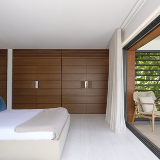 Step into your serene retreat with crisp white linens, warm wood tones, and a private balcony where you can unwind in woven chairs overlooking lush garden views.