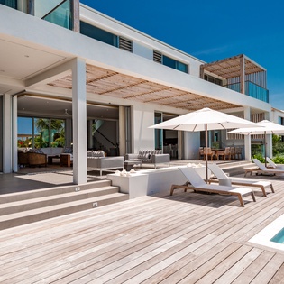 Modern beachfront villa featuring expansive deck terrace with private pool and covered outdoor living space overlooking tropical surroundings.