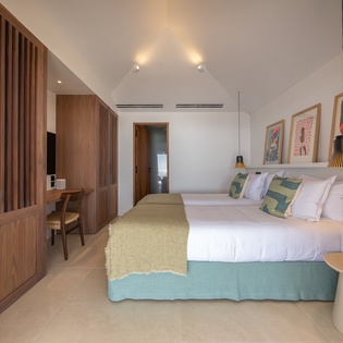 Sink into your serene bedroom sanctuary with warm wood accents, vibrant artwork, and a plush teal bed that promises restful nights.