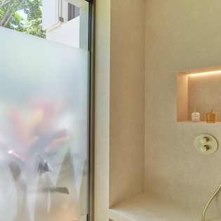 Step into your spa-like shower with golden fixtures and built-in niche for toiletries, offering privacy while staying connected to nature.