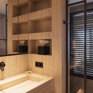 Unwind in your luxurious stone-carved bathtub, surrounded by warm wood shelving and sleek black fixtures for the ultimate spa-like retreat.