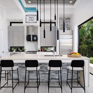 Picture yourself cooking in this stunning modern kitchen with a sleek marble island, pendant lighting, and refreshing garden views through floor-to-ceiling glass doors.