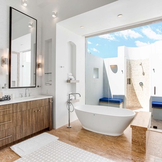 Soak in the freestanding tub while natural light pours in, or step through glass doors to your private outdoor shower with blue-tiled seating and open-air bliss.