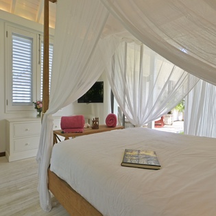 Drift off under romantic mosquito netting in your serene bedroom sanctuary, where tropical breezes flow through shuttered windows.