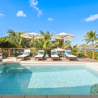 Private pool terrace surrounded by tropical palms with ocean views and comfortable loungers for ultimate relaxation.