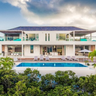 Modern luxury villa showcasing contemporary architecture with pristine pool and tropical landscaping in a serene natural setting.