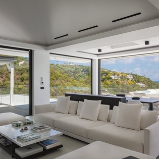Unwind in your stunning living room where floor-to-ceiling windows frame breathtaking ocean views, creating the perfect backdrop for relaxation.