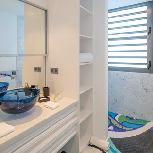 Indulge in your private spa-like bathroom featuring stunning blue vessel sinks, marble finishes, and a colorful mosaic shower floor.