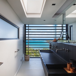 Soak in your sleek bathtub while gazing at stunning turquoise waters through floor-to-ceiling windows in this luxury bathroom.