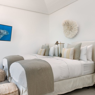 Slip into your serene twin beds with soft linens and ocean-inspired art creating the perfect coastal retreat.