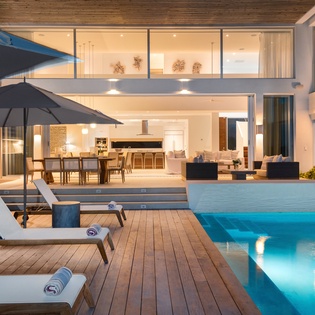 Unwind by your private pool with stunning views into the open-plan living spaces, where warm evening lights create the perfect ambiance for relaxation.