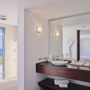 Indulge in your private spa-like bathroom with dual vanities, rainfall shower, and breathtaking ocean views from floor-to-ceiling windows.