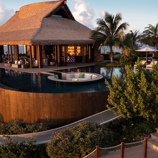 Tropical paradise featuring traditional thatched-roof architecture with modern luxury amenities and lush landscaping.