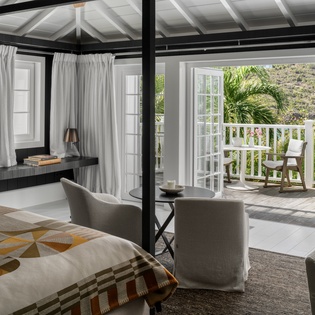 Unwind in your stylish bedroom with exposed beams and French doors opening to your private balcony overlooking lush tropical gardens.