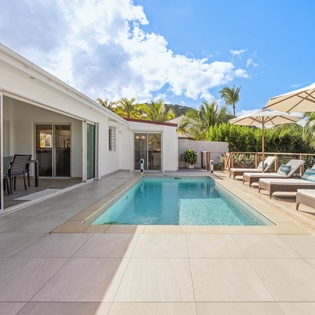 Your private poolside paradise awaits with crystal-clear waters, comfortable loungers, and tropical shade umbrellas.