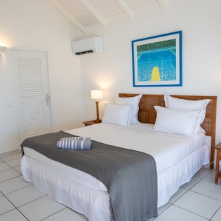 Drift off to sleep in your serene bedroom with crisp white linens, warm wood accents, and gentle lighting creating the perfect island retreat.