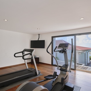 Your private fitness haven awaits with modern equipment and natural light streaming through floor-to-ceiling windows.