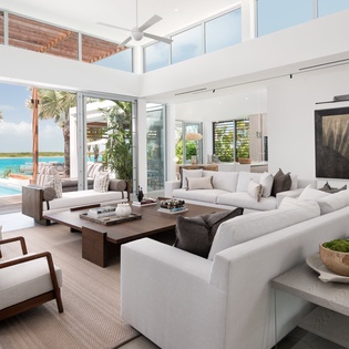 Your spacious living room opens to paradise through floor-to-ceiling windows, revealing turquoise waters and swaying palms just steps away.