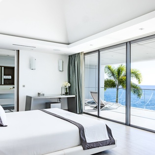 Wake up to endless ocean views through floor-to-ceiling windows in this luxurious bedroom with stunning sea panoramas.