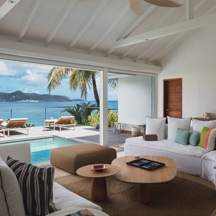Unwind in your bright, airy living space where plush seating and tropical breezes invite relaxation. Floor-to-ceiling windows frame stunning ocean views and your private pool terrace.