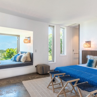 Unwind in your stylish bedroom with stunning sea views through the picture window. Cozy blue linens and warm pendant lighting create the perfect retreat.