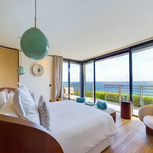 Wake up to breathtaking ocean views through floor-to-ceiling windows in your serene bedroom retreat with modern coastal design.