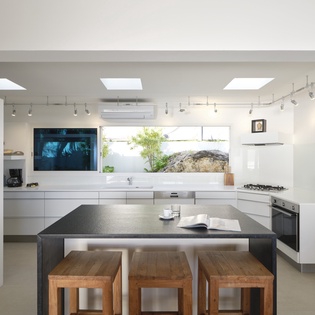 Step into this stunning modern kitchen where sleek white cabinetry meets natural light from skylights above, creating your perfect culinary sanctuary.