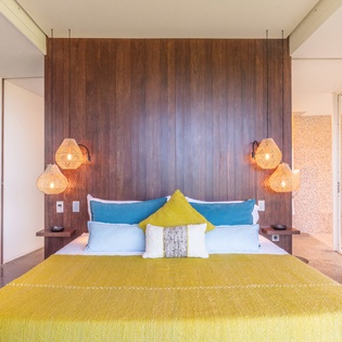 Unwind in your stylish bedroom with warm woven lighting and vibrant pops of color creating the perfect tropical retreat.