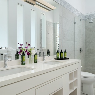 Step into this pristine bathroom where sleek tile and elegant finishes create a serene spa-like atmosphere. Fresh flowers and luxury amenities await your arrival.