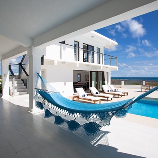 Unwind in your hammock by the pool with stunning ocean views stretching endlessly before you—modern luxury meets Caribbean relaxation.