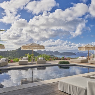 Stunning infinity pool with panoramic ocean and mountain views creates the perfect tropical paradise backdrop.
