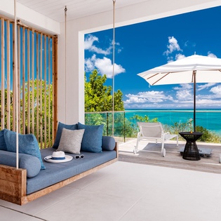 Unwind on your stunning ocean-view terrace with a unique hanging daybed and pristine white furnishings overlooking turquoise waters.