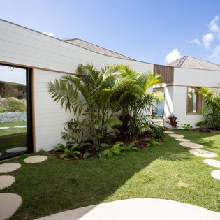 Modern tropical architecture surrounded by lush landscaping and winding stone pathways creating a serene coastal retreat.