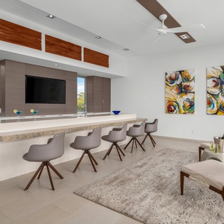 Relax in this stunning open-concept space where modern kitchen meets elegant lounge, perfect for entertaining with vibrant art and tropical views.