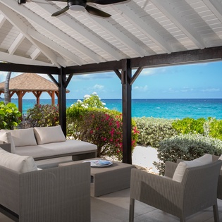 Sink into plush seating under your private cabana, where turquoise waters and lush tropical gardens frame your perfect beachfront escape.
