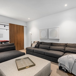 Sink into plush sectional seating while your game room beckons beyond sleek sliding doors—perfect for unwinding after adventures.