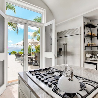Your gourmet kitchen opens to a sun-soaked patio with mountain views, perfect for indoor-outdoor living while you cook and entertain in tropical paradise.