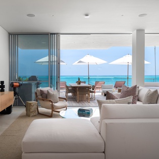 Relax in your stunning oceanfront living room where floor-to-ceiling windows frame endless turquoise waters and your private terrace awaits.