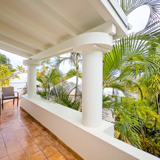 Step onto your private balcony and soak in the lush tropical surroundings. Relax in the cozy seating area while vibrant palms frame serene garden views.