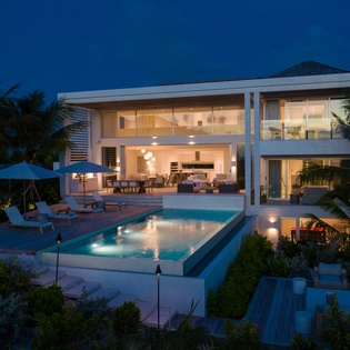 Stunning contemporary villa showcases modern architecture amid tropical palms, featuring sleek pool and elegant indoor-outdoor living spaces.