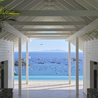 Caribbean villa entrance frames stunning ocean views with pristine waters and distant mountain silhouettes.