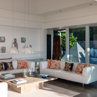 Sink into plush white sofas surrounded by warm natural light and stylish decor in your serene living space.