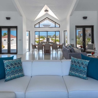 Sunlight pours through soaring windows, bathing your open-plan living space in warmth. Relax on plush sofas, gather at the dining table, and enjoy serene views that bring the outdoors in.