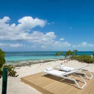 Private beachfront deck with loungers awaits your tropical escape on pristine white sands.