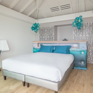 Drift into dreams under soaring beamed ceilings where turquoise glass chandeliers cast a serene glow over your plush retreat.