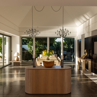 Step into your open-plan sanctuary where modern elegance meets warm natural light streaming through floor-to-ceiling windows overlooking lush greenery.