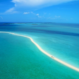 Aerial view of pristine turquoise waters and sandy beach formations in the surrounding tropical paradise area.